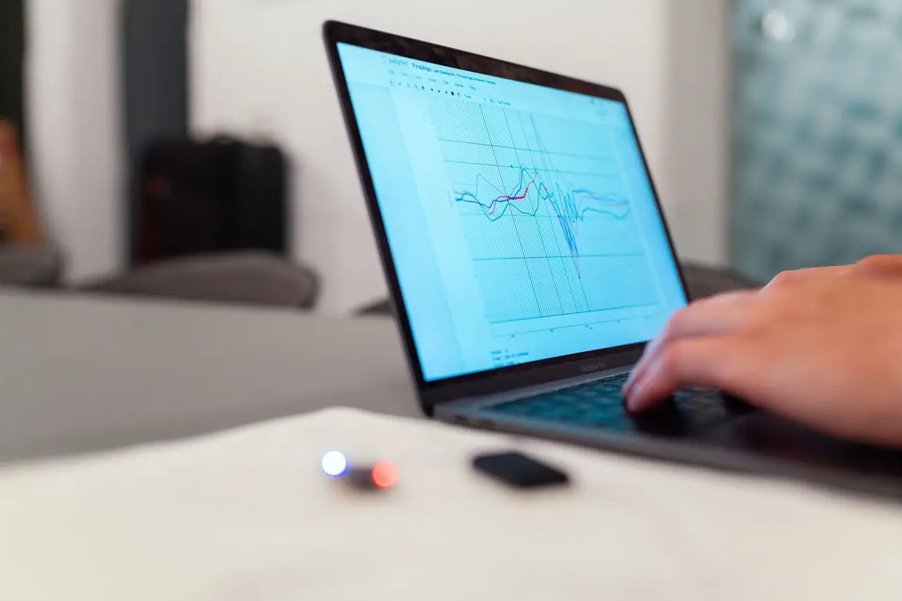 Hands working on a laptop with a data chart