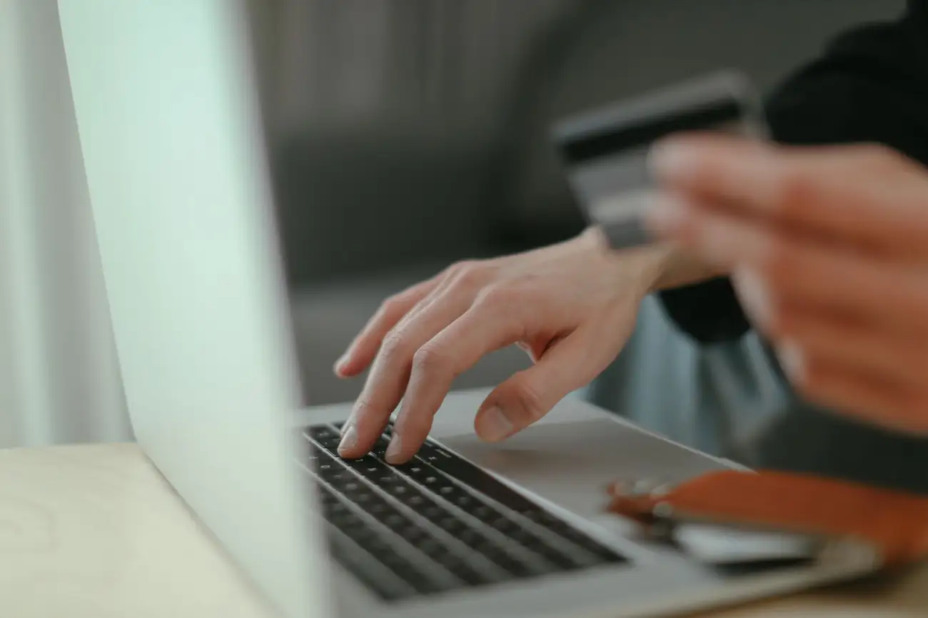 Hands typing at a laptop holding a bank card