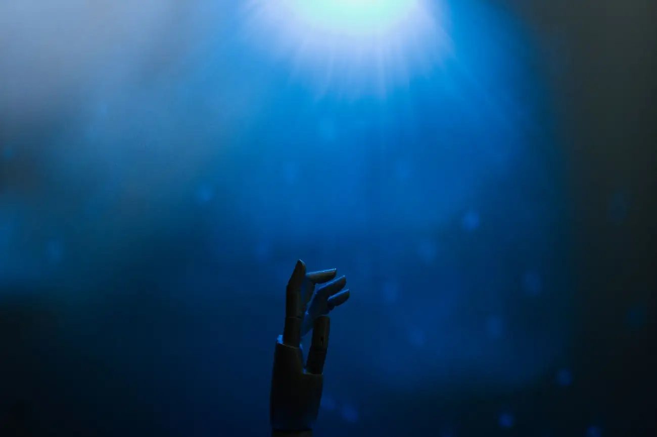 Robotic hand silhouette reaching toward light